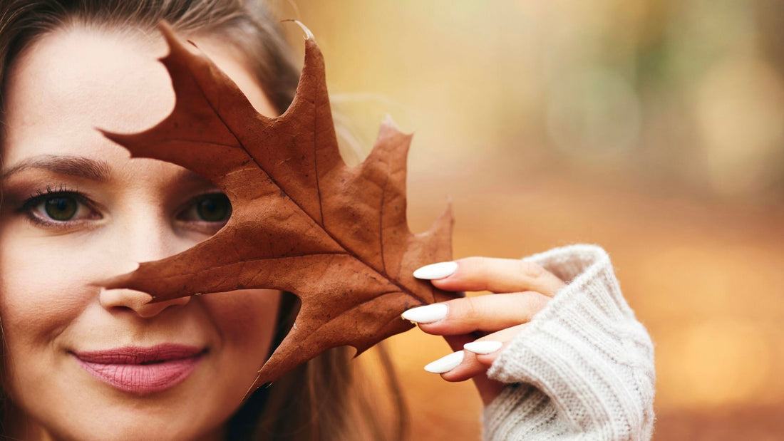 Woman holding autumn leaf to face