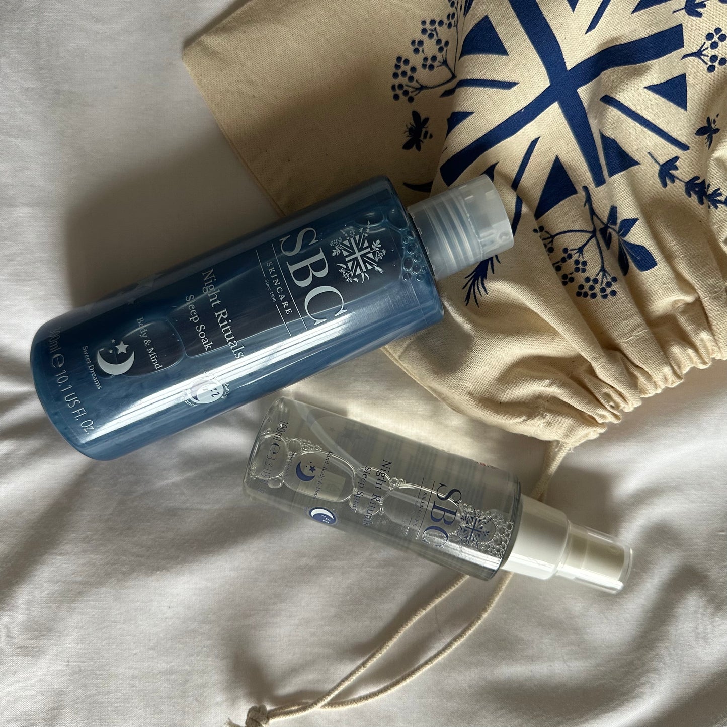 SBC Skincare's Night Rituals Sleep Soak and Spray on a white linen sheet with cotton bag