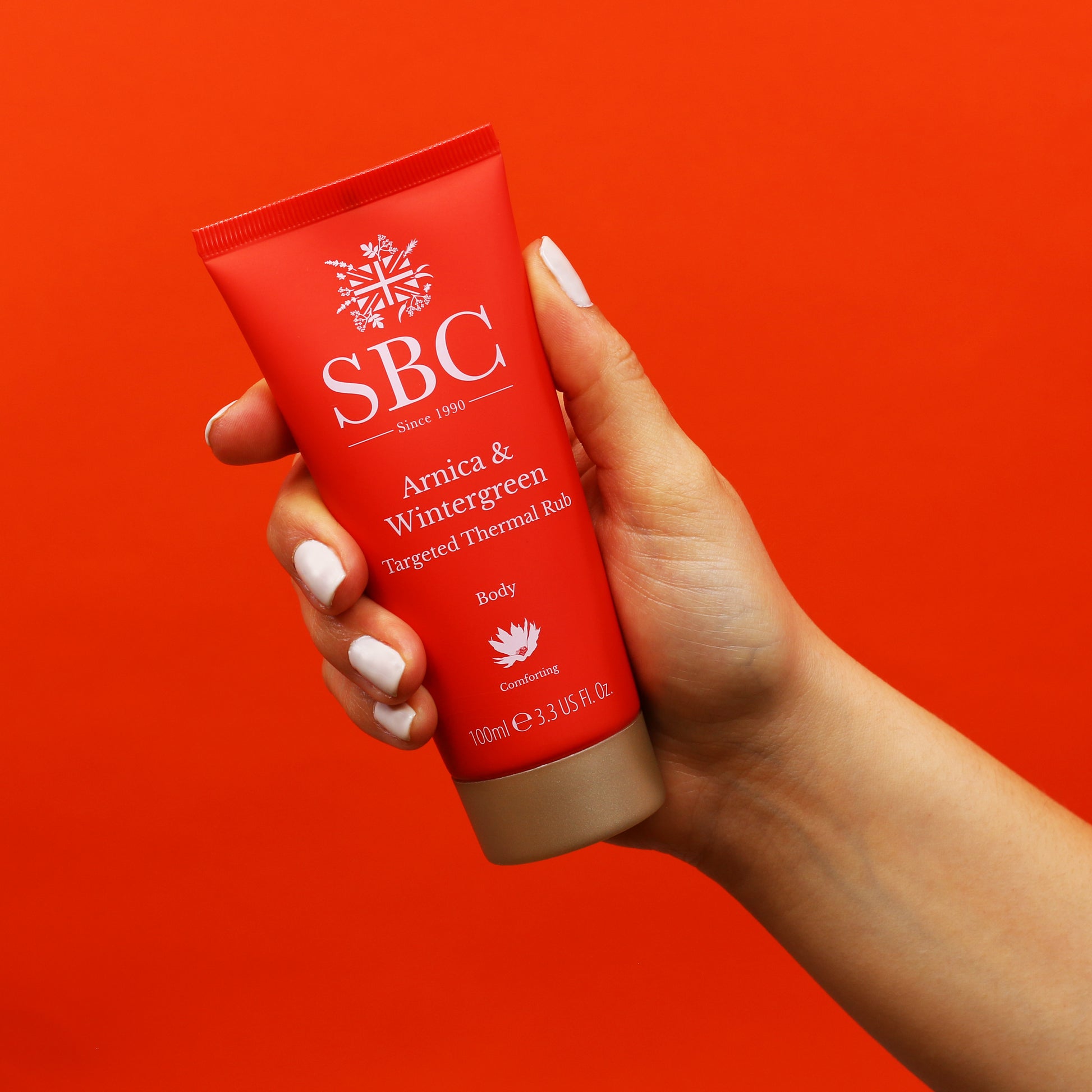Arnica & Wintergreen Thermal Rub being held in front of a red background