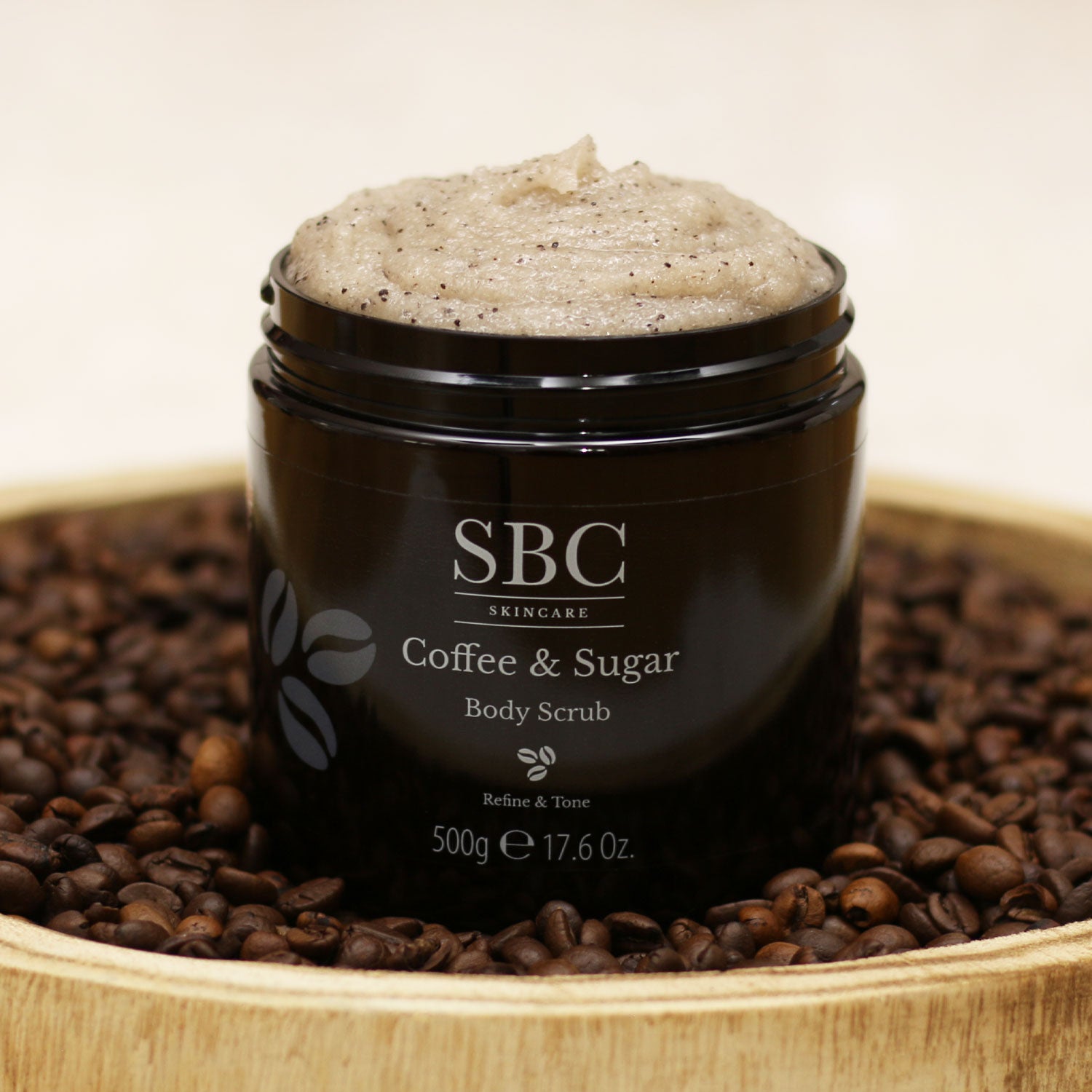 Coffee & Sugar Body Scrub in a wooden tray with coffee beans