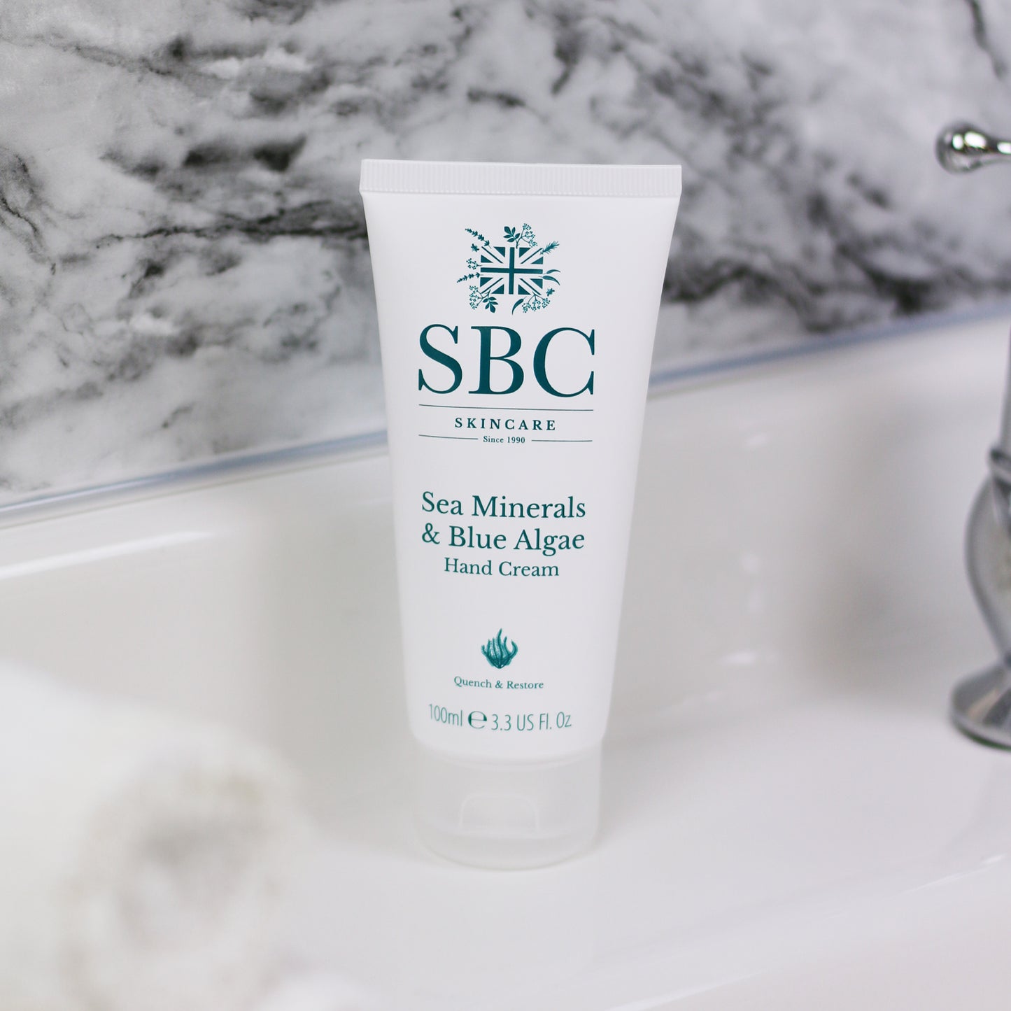 Sea Minerals & Blue Algae Hand Cream on a bathroom sink with a marble backsplash 