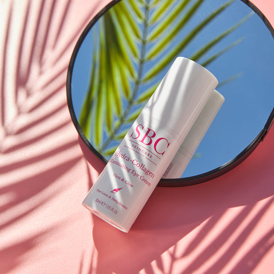 Hydra-Collagen Illuminating Eye Cream on a mirror with palm leaf shadows