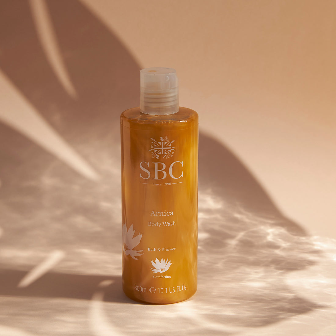 Arnica Body Wash on a beige background with monstera leaf shadows