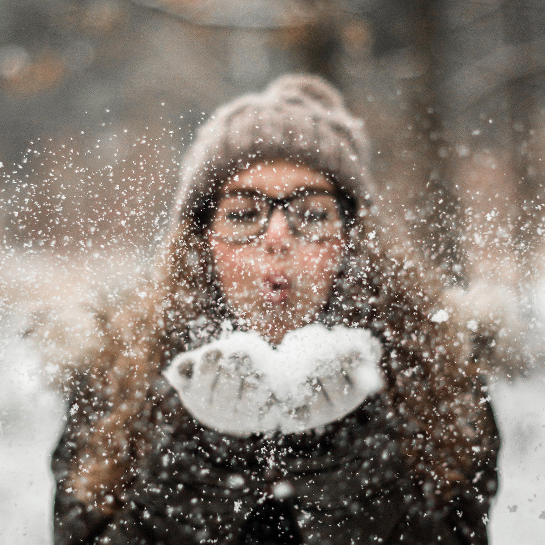 woman blowing snow off of hands 