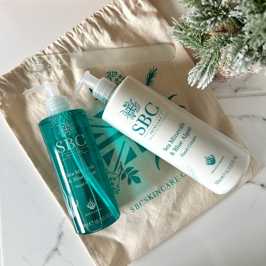 SBC Skincare's Sea Minerals & Blue Algae Hand Wash and Hand Cream on a marble bathroom counter with nail file and christmas tree 
