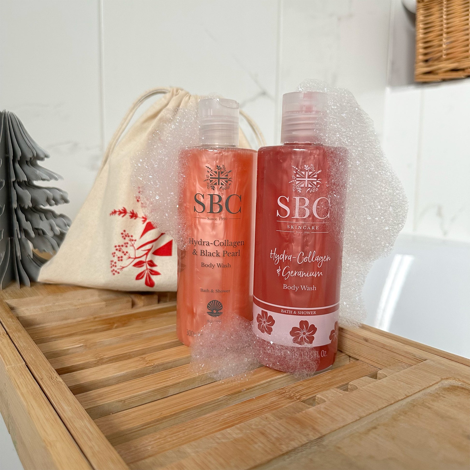 SBC Skincare's Hydra-Collagen & Geranium and Hydra-Collagen and Black Pearl Body Wash on a wooden bath caddy
