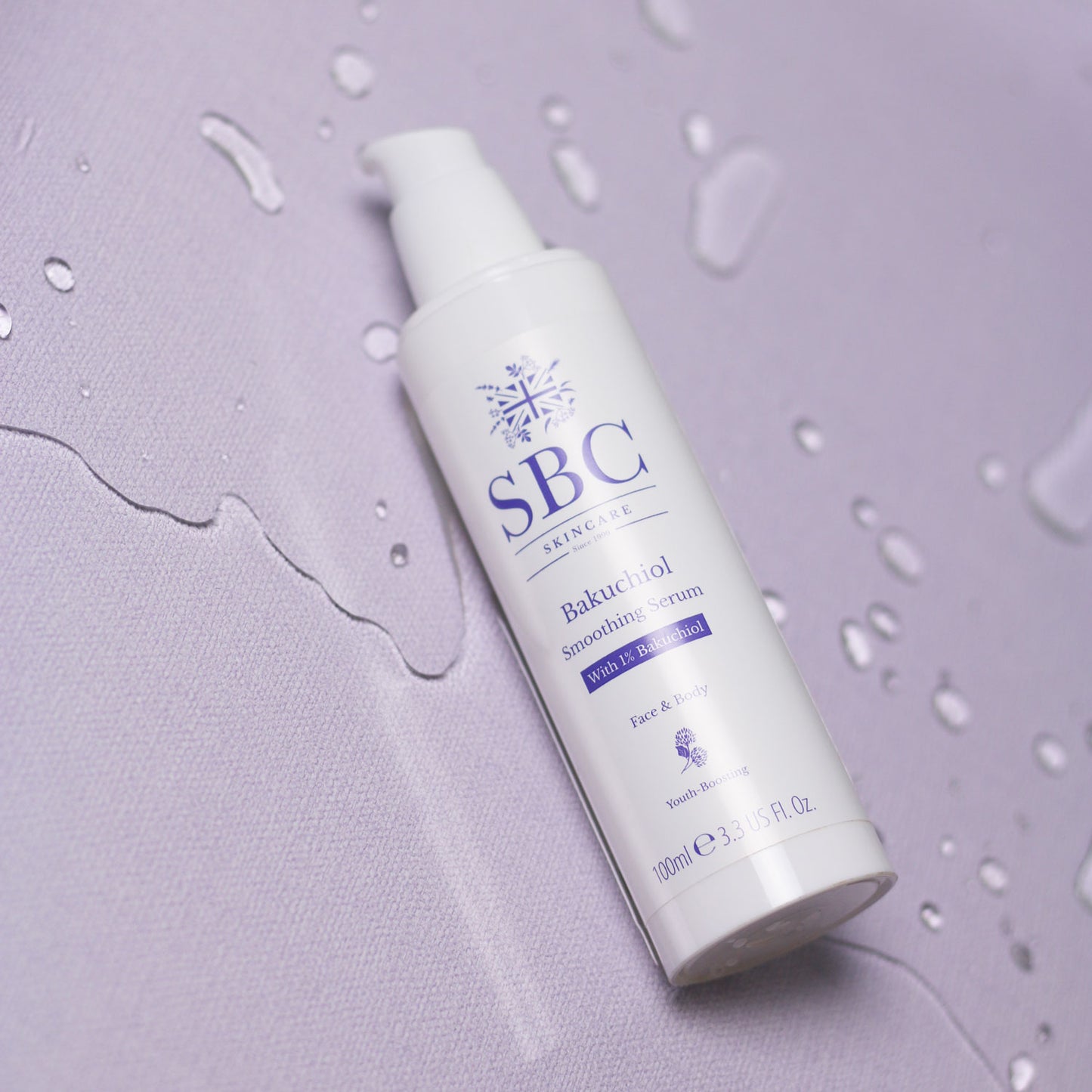 Bakuchiol Smoothing Serum laying on a purple surface with splashes of water