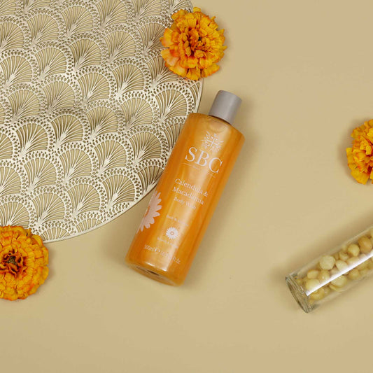 SBC Skincare's Calendula & Macadamia Body wash on a beige background with Calendula Flowers 