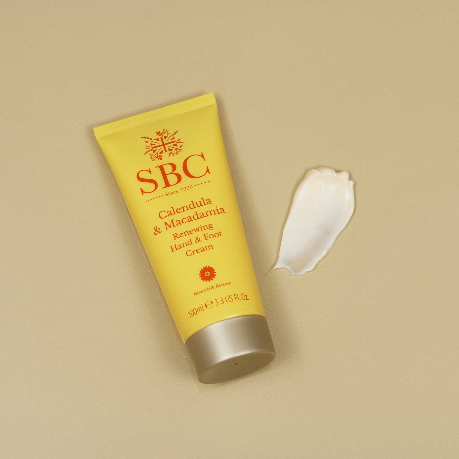 Calendula & Macadamia Hand & Foot Cream with a swatch on a beige background 