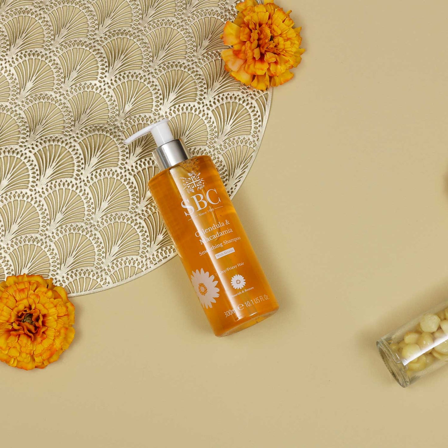 300ml Calendula & Macadamia Shampoo on a beige background with calendula flowers and gold accents 