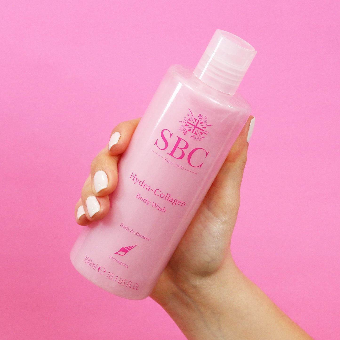 300ml of SBC Skincare's Hydra-Collagen Body Wash being held in front of a pink background 
