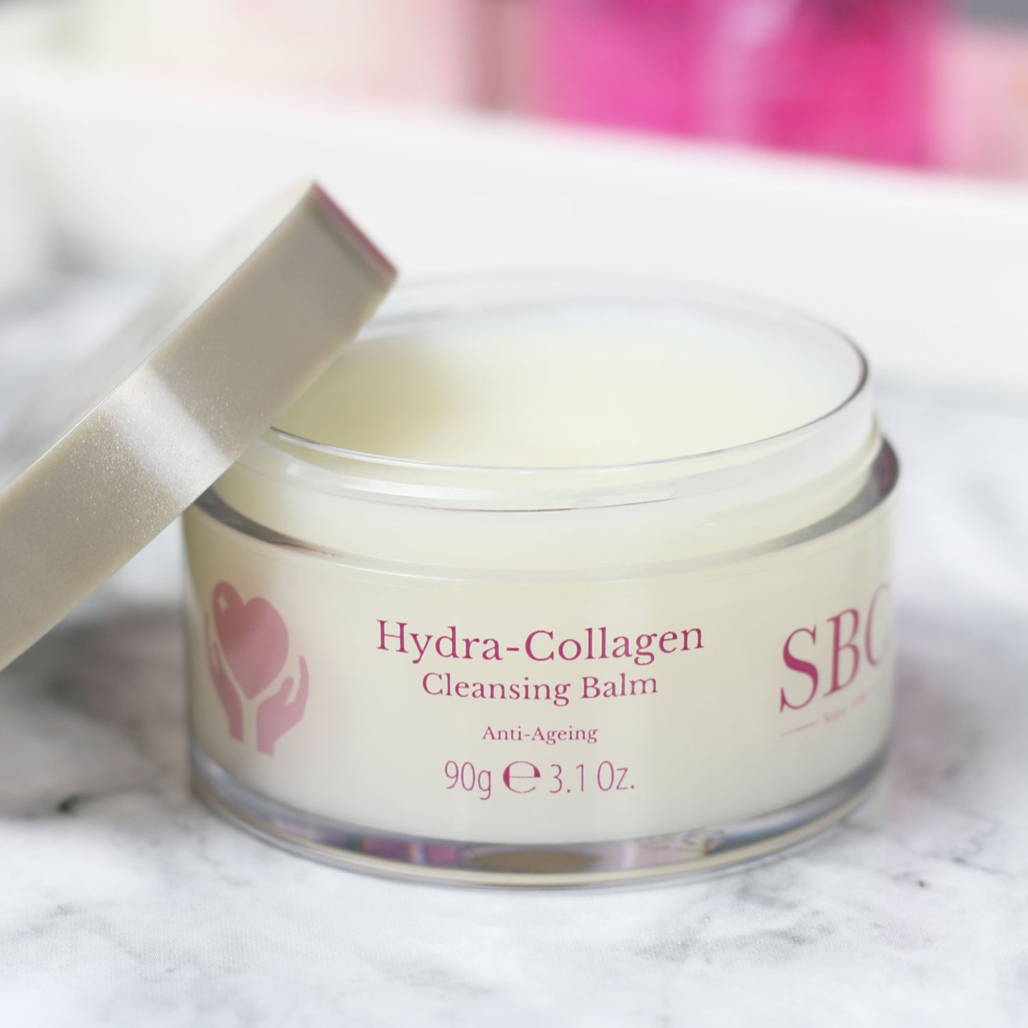 Hydra-Collagen Cleansing Balm with its cap off on a marble counter 