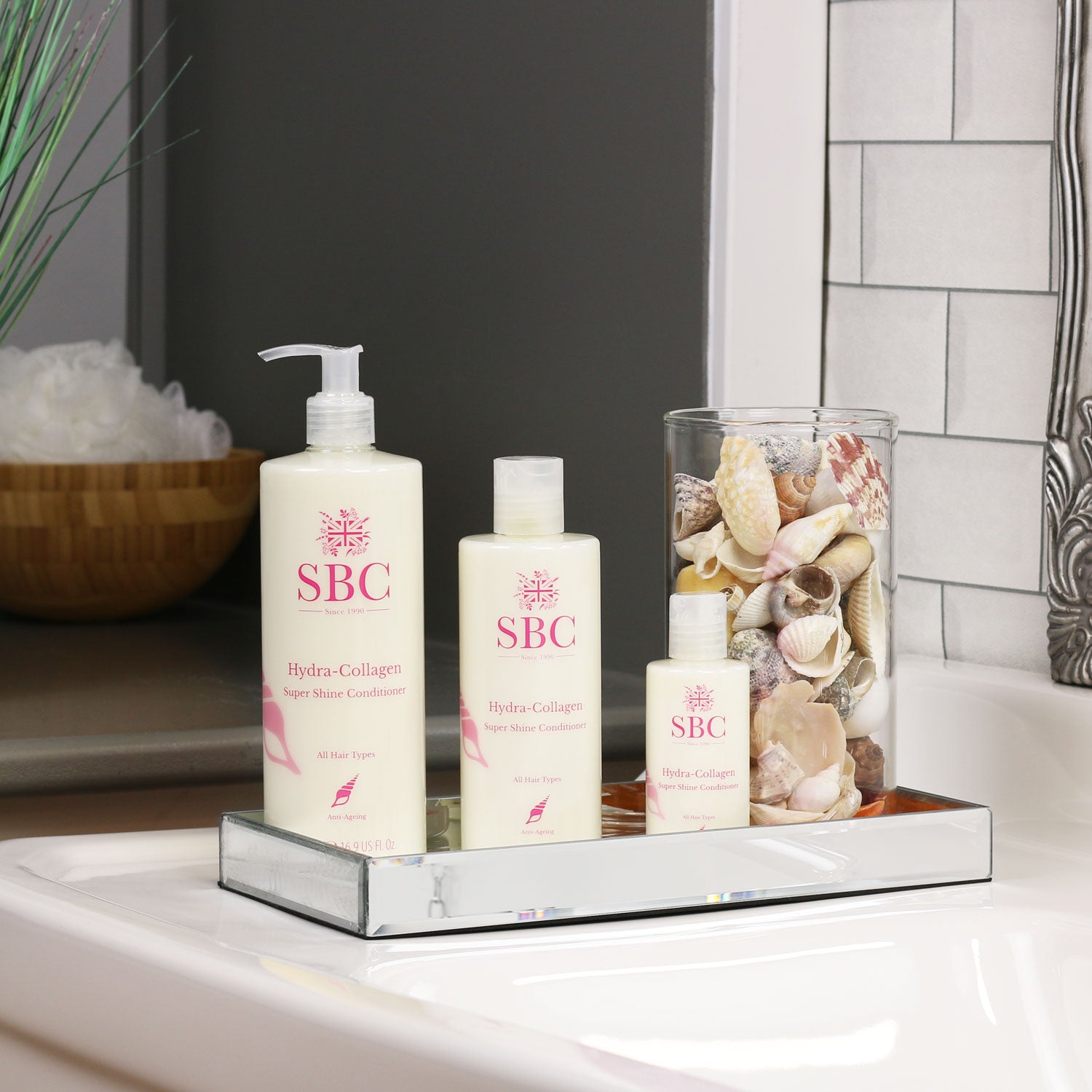 500ml, 300ml and 100ml Hydra-Collagen Super Shine Conditioner in a mirrored dish on a bathroom sink