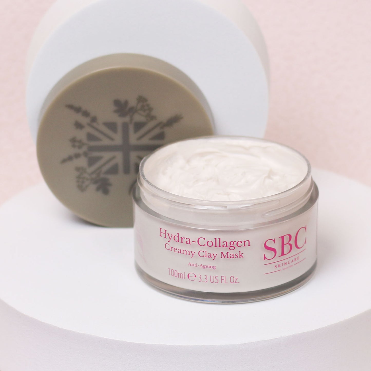 Hydra-Collagen Creamy Clay Mask with its lid off on a white stand 