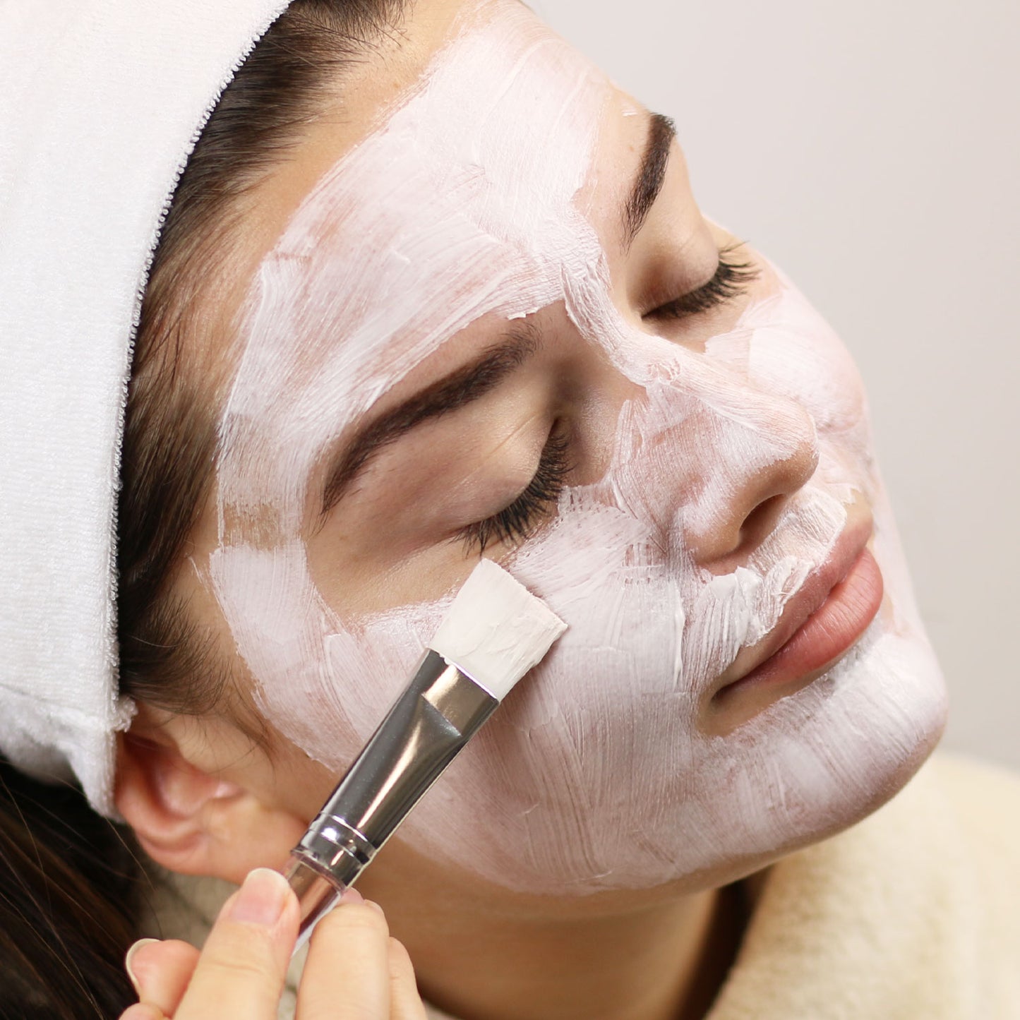 Woman applying Creamy Clay Mask to face with brush 
