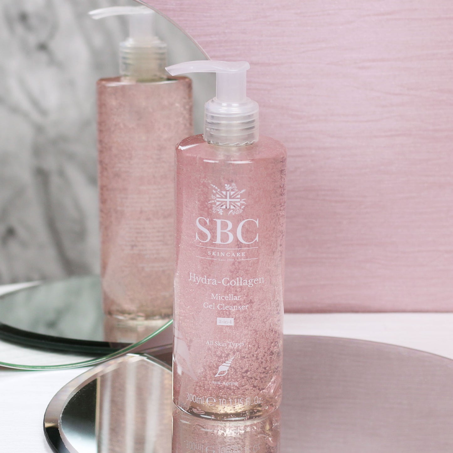 Hydra-Collagen Micellar Gel Cleanser on a mirror with a pink textured background 