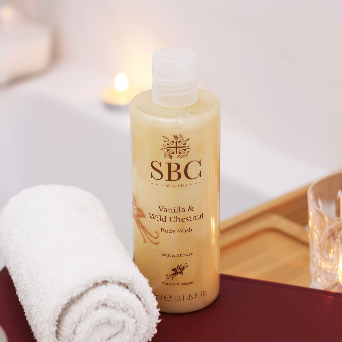 Vanilla & Wild Chestnut Body Wash on a wooden bath caddy with a book and a towel 