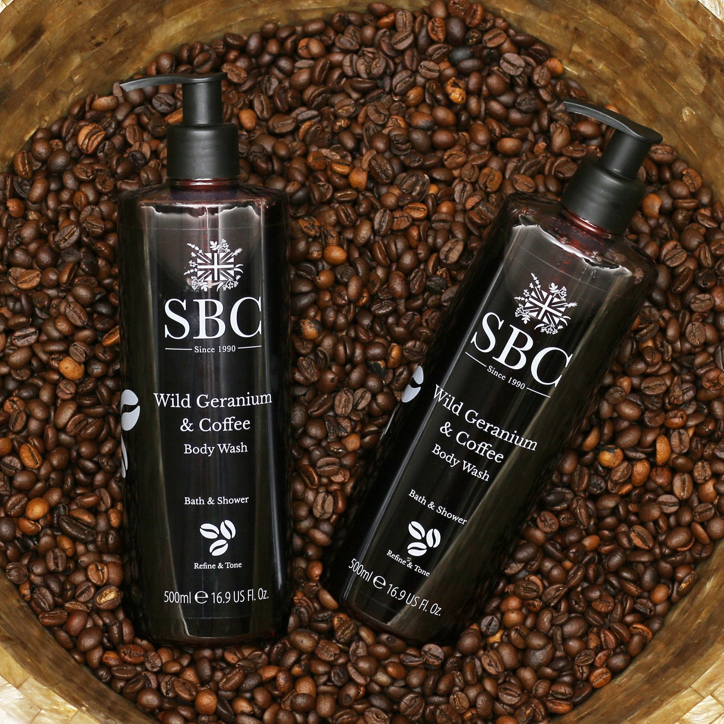 Two Wild Geranium & Coffee Body Wash in a bowl of coffee beans 