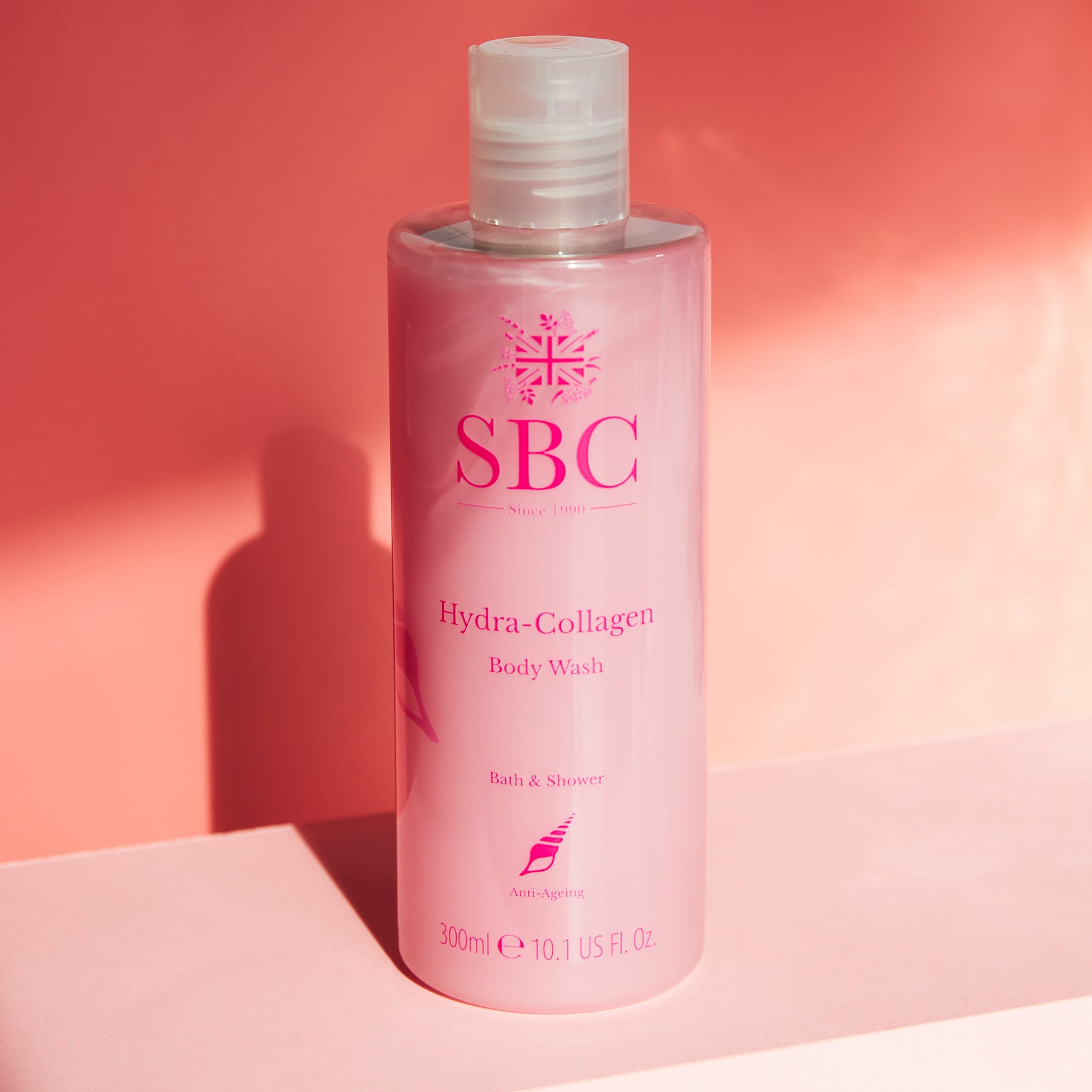 300ml of SBC Skincare's Hydra-Collagen Body Wash on a peachy pink background in the sunlight