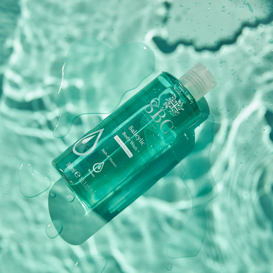 Salicylic Body Wash on a pale blue surface with water splashes